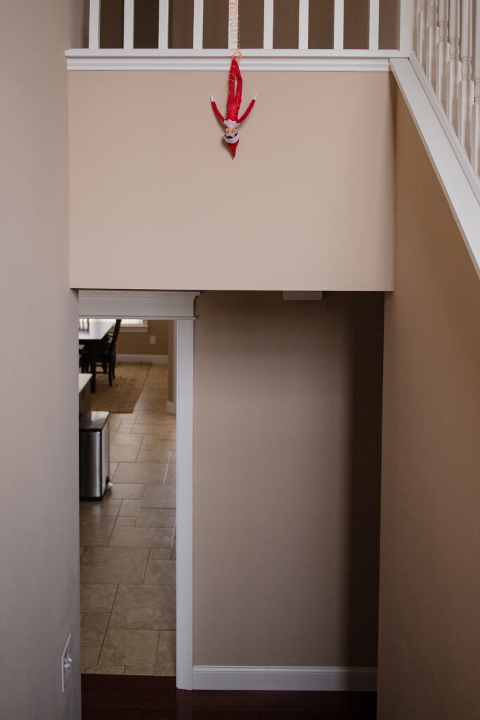 Elf on the Shelf hanging upside down from banister 