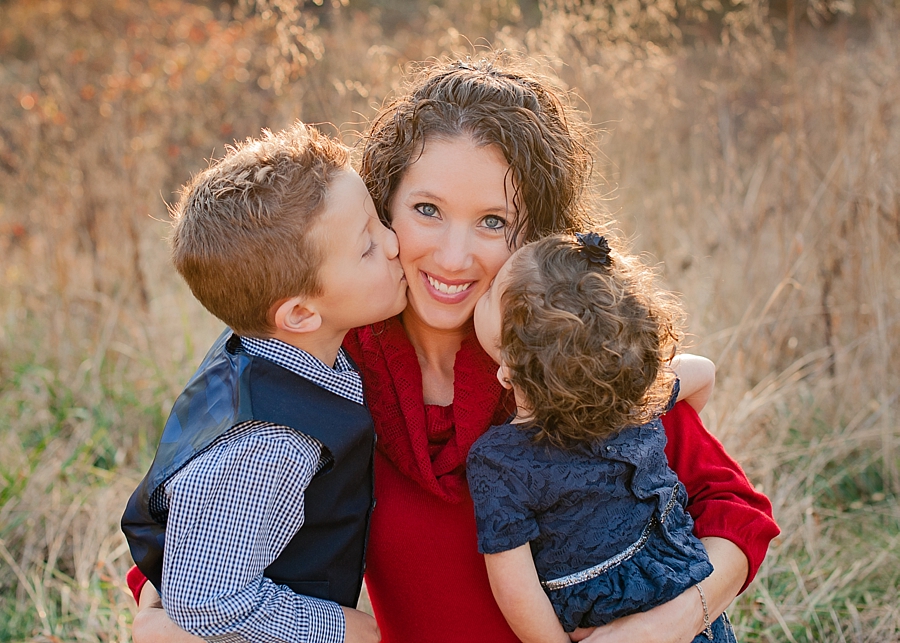Two little kids kissing on mommy's cheeks outdoor field photo