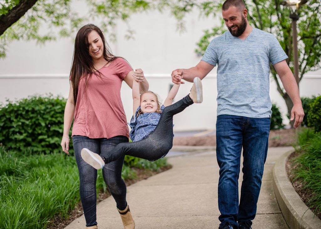 man woman swinging child, mom and dad swinging daughter, family portrait