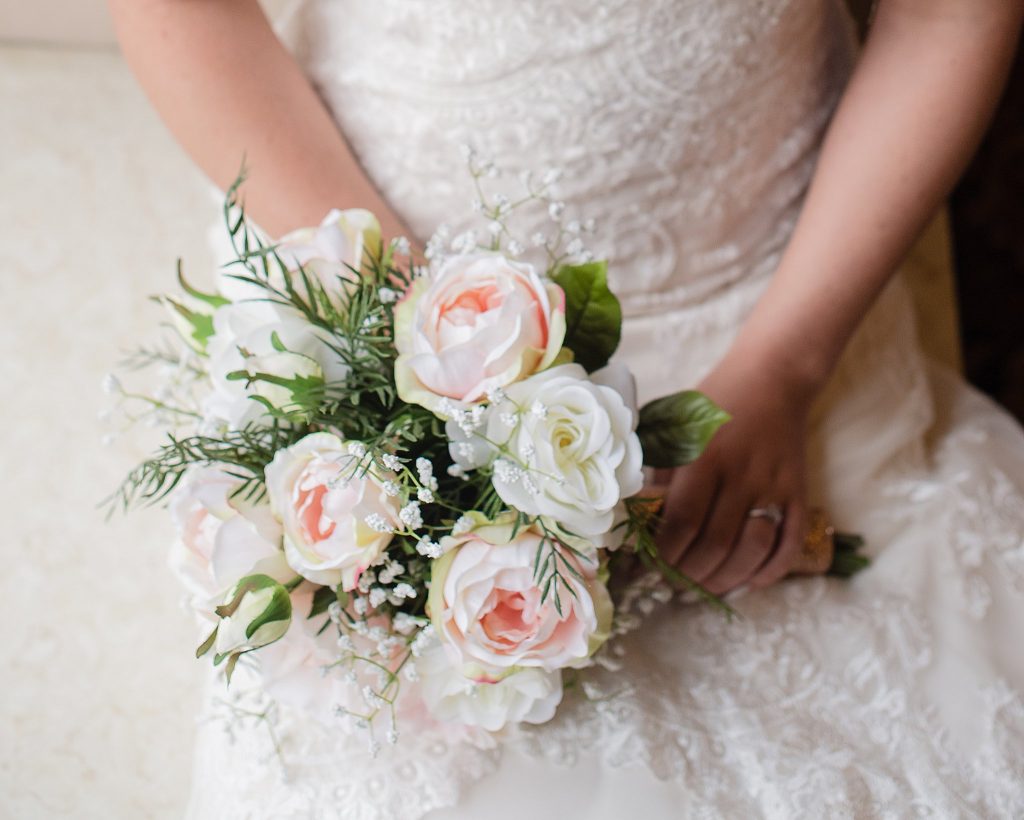 detail show of bridal bouquet sitting on wedding dress