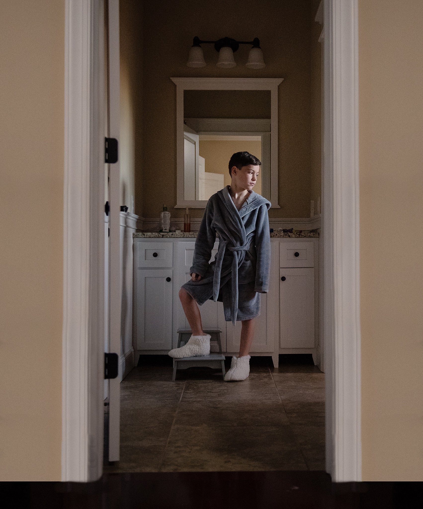 A boy in a robe stands at the bathroom doorway as if posing for a fashion magazine.