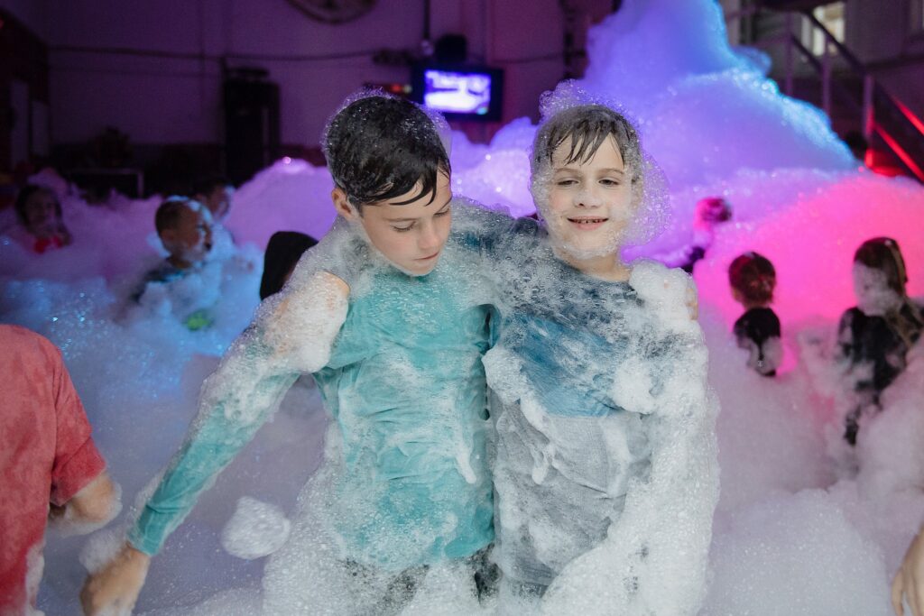 two boys pose together in foam party 