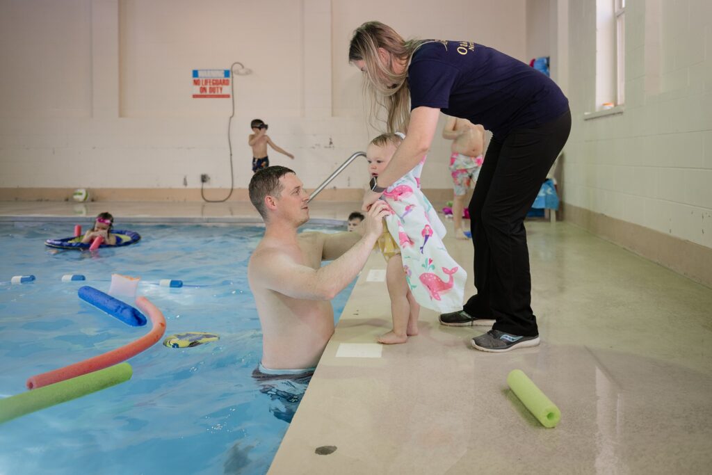 parents help baby put on towel around the sacred heart retreat pool