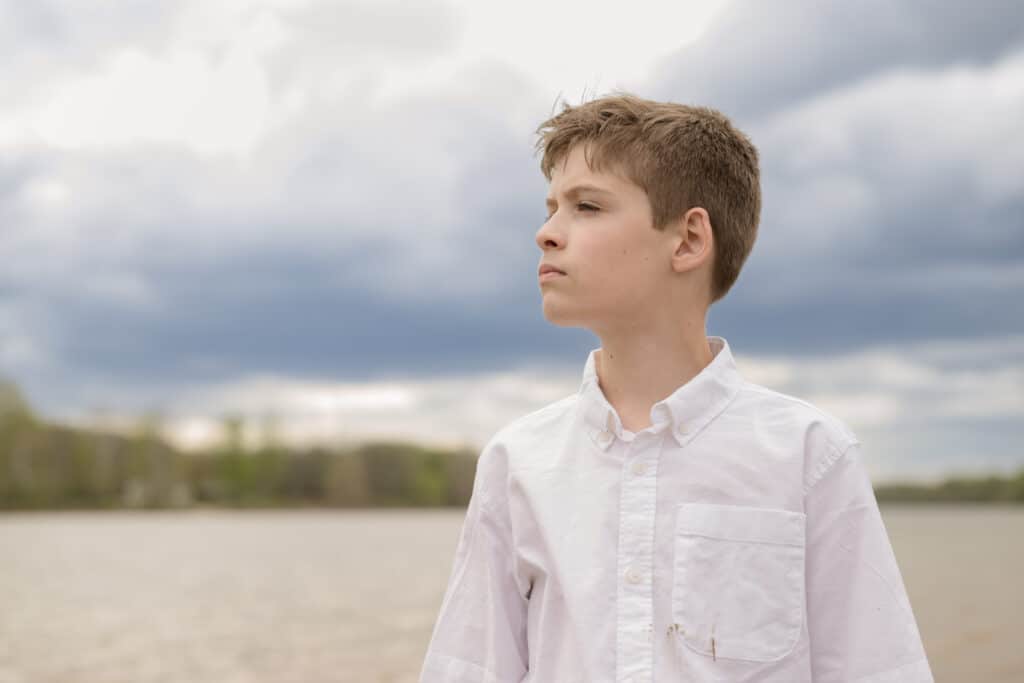 boy looking off to the side with blue sky behind him