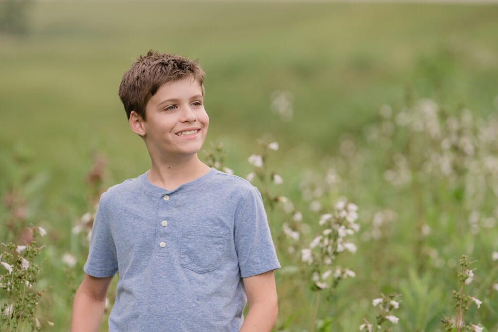 Boy looking to the side with a flower field behind him.  Field near Marietta, OH
