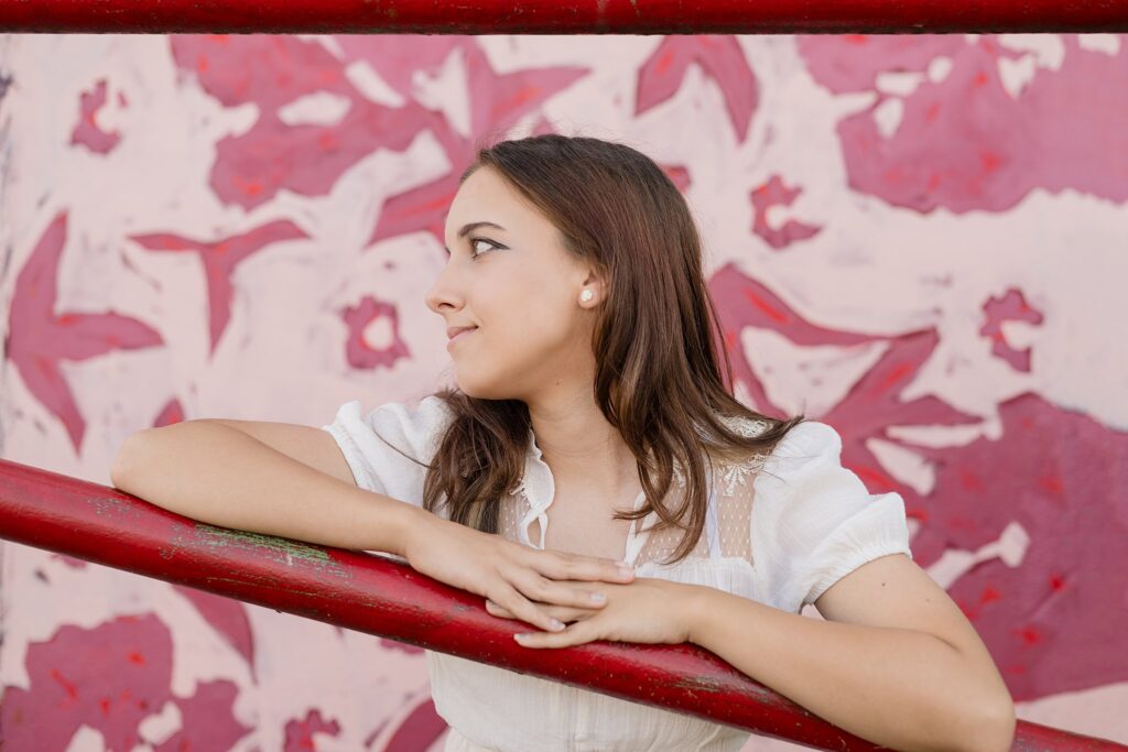 A girl facing to the left smiling with a pink background for her Senior Pictures near Marietta, OH.  She is a Parkersburg South High School student.