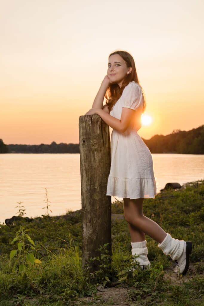 Girl posing near water leaning on a wooden post for her senior photography session near marietta oh