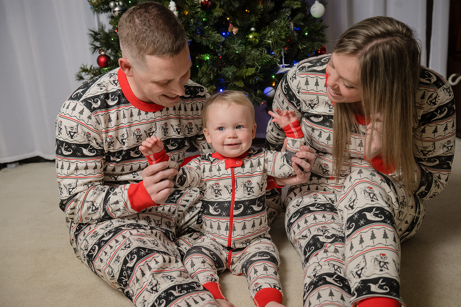 family in matching christmas pjs in front of christmas tree