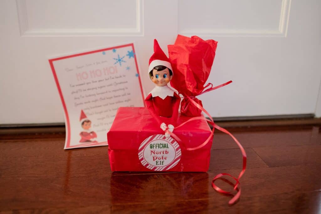Elf on the Shelf arriving in a box wrapped in red tissue paper and ribbon