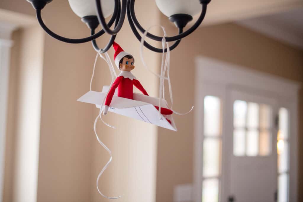 elf on the shelf gliding in on a paper airplane