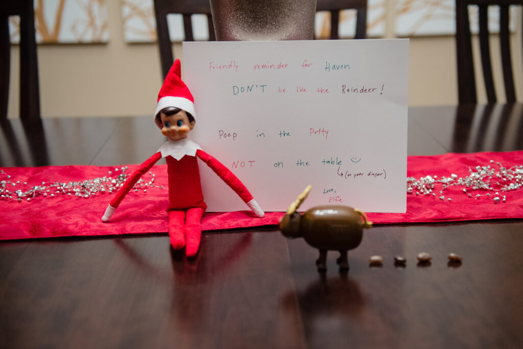Elf on the Shelf sitting with a pooping reindeer
