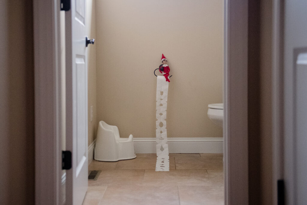 elf o the shelf sitting on roll of ltoilet paper that has been cut to look like a snowflake