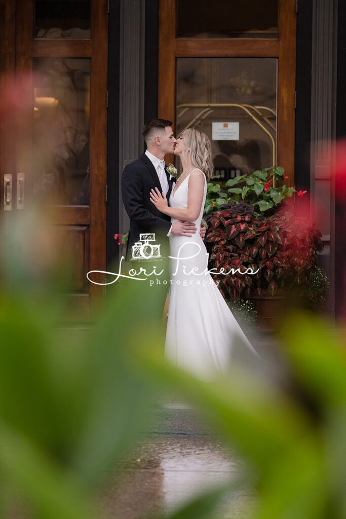 Newlyweds kiss at the front entrance to a hotel