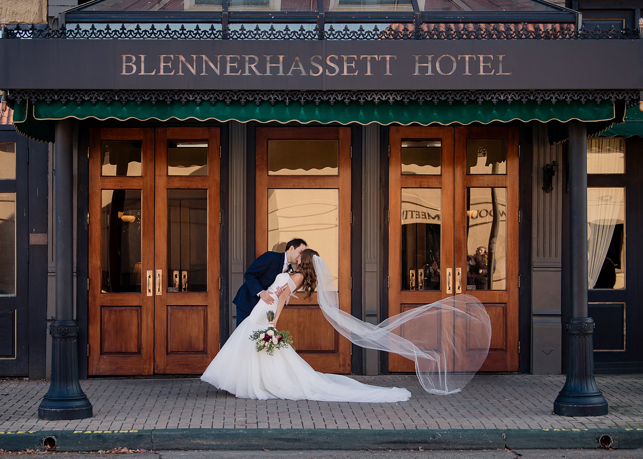 Newlyweds kiss under the front facade of the Blennerhassett Hotel wedding venue