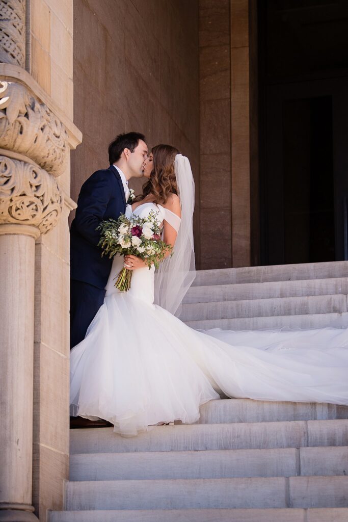 Newlyweds kiss on a large ornate stairway at a Blennerhassett Hotel wedding