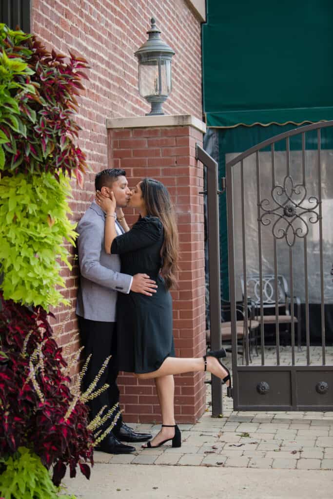 New engaged couple kisses against a brick wall in an alley after visiting hair salons parkersburg wv