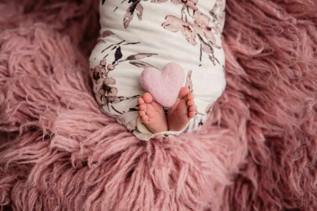 pink sheep rug with baby swaddled and its feet sticking out with a little heart