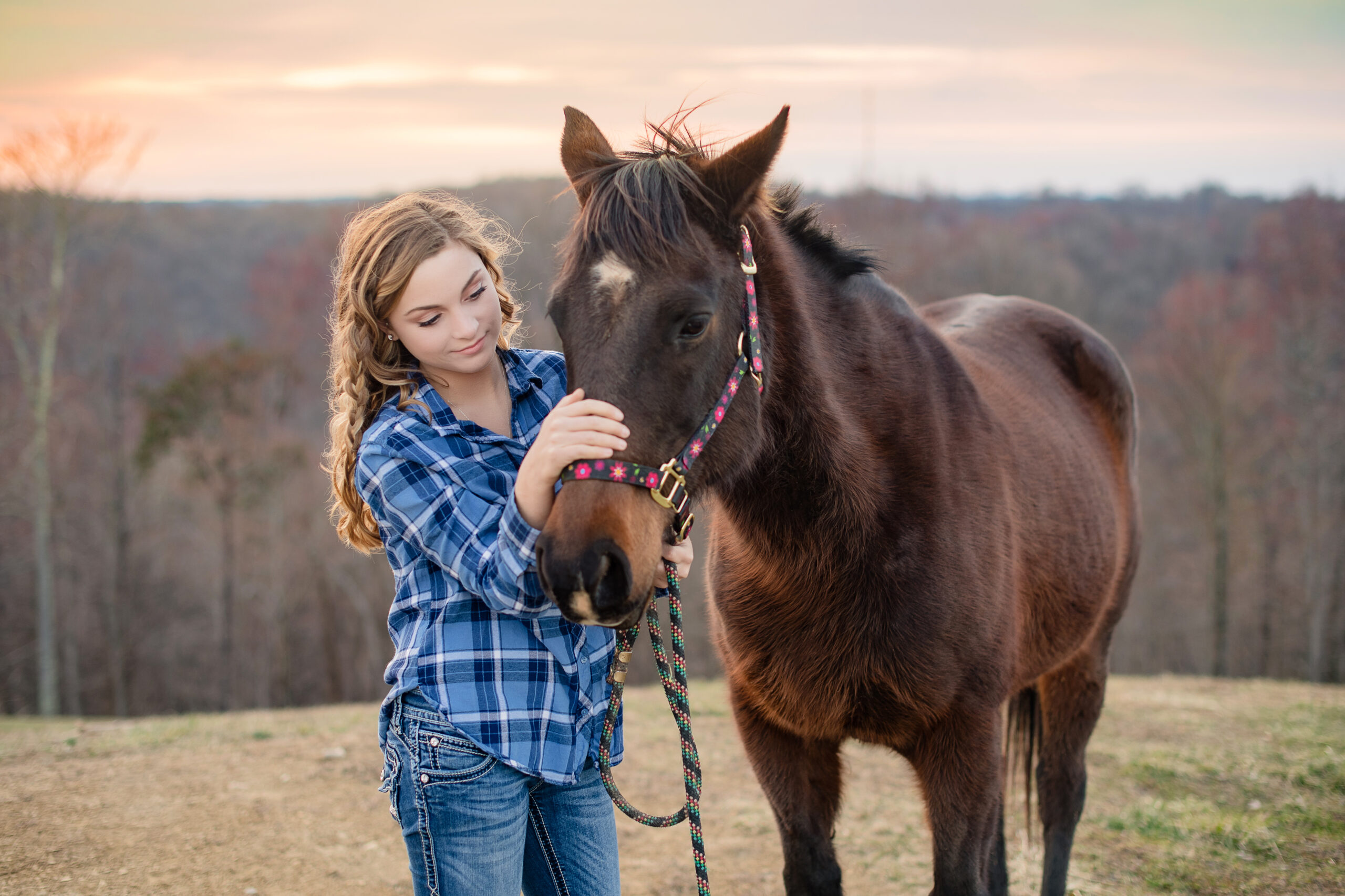 girls standing in a field with her horse for a senior photography session