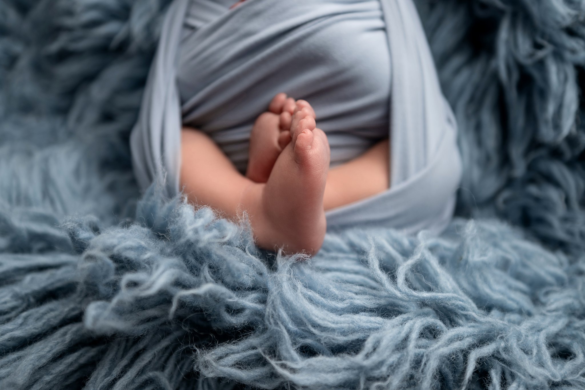 Details of a newborn baby's feet in a blue swaddle