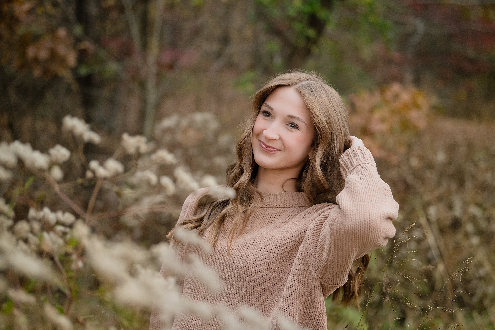 A high school senior in a tan sweater smiles while pulling back her hair after enjoying WVUP Early College